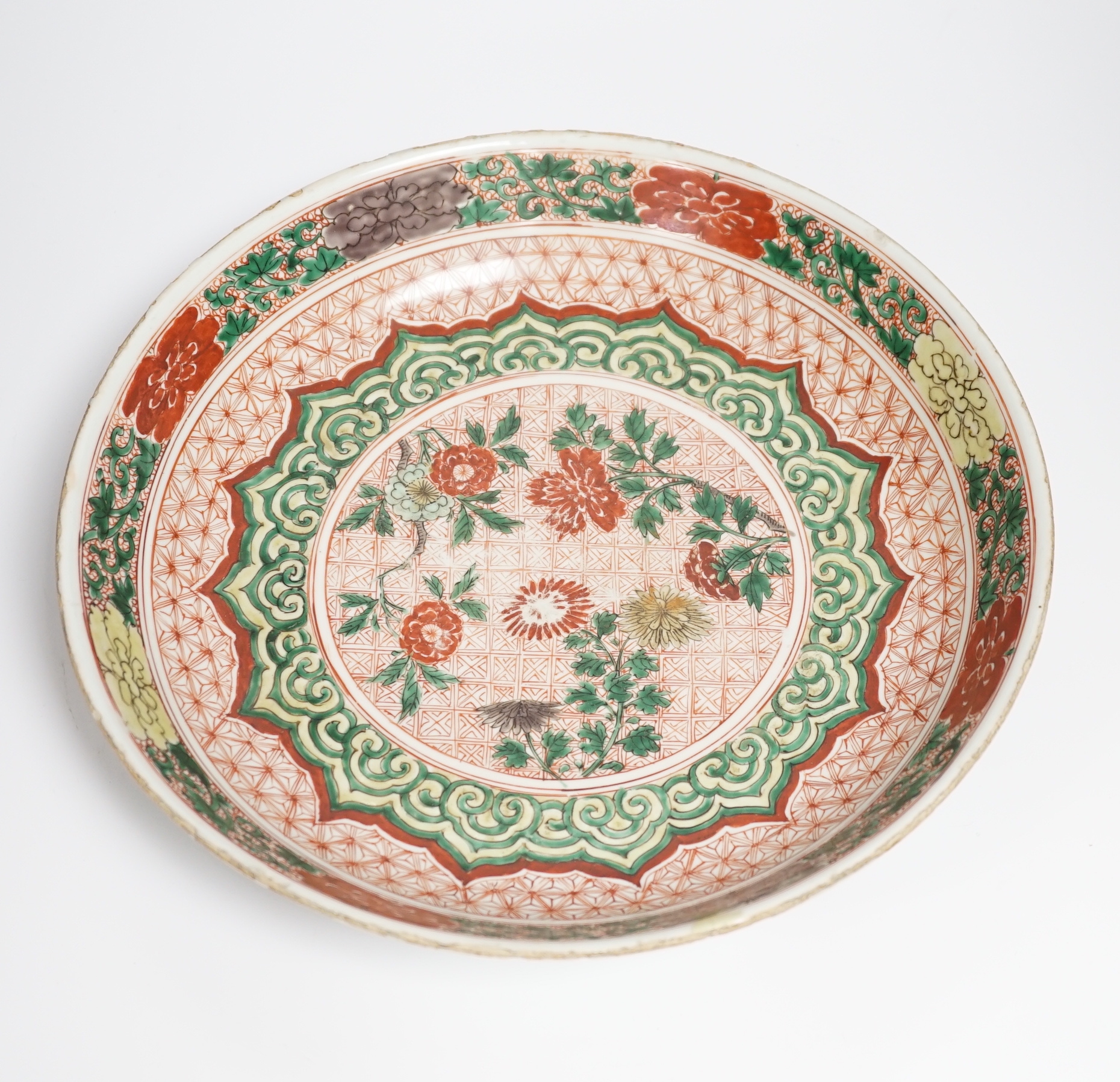 A Chinese famille verte dish, Kangxi period, decorated with flowers bands of brocade patterns, channel moulded foot, 33cm diameter